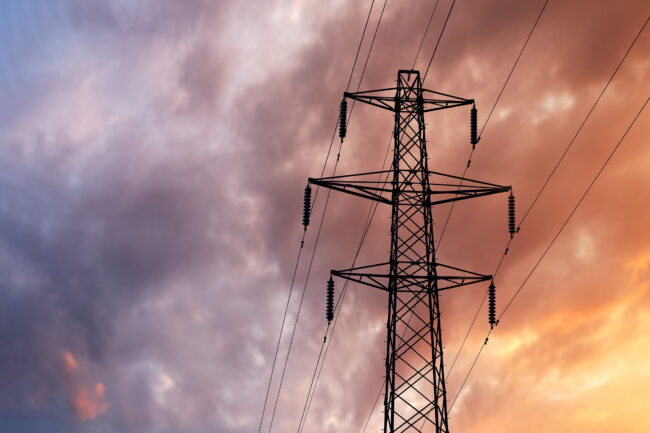 Detail of a British Style Electricity Pylon and suspended electic cables against a Blue Cloudy Sky